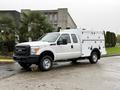 A 2015 Ford F-350 SD white utility truck with a custom service body and a crew cab design