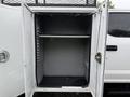 A white 2020 Ford F-550 truck with open compartment doors revealing an empty storage area inside