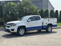 A 2017 Chevrolet Colorado with a white body and blue accents featuring a utility bed and chrome wheels parked on a concrete surface