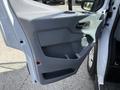 A close-up view of the interior door panel of a 2018 Ford Transit featuring gray plastic with a handle and storage compartment