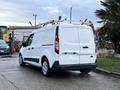 A 2017 Ford Transit Connect van with a white exterior and a ladder rack on the roof parked in a lot