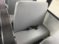 A row of gray bus seats with a black seatbelt attached to the side of one seat in a 2022 Freightliner B2 bus