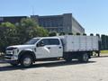 A 2019 Ford F-550 flatbed truck with a metallic dump bed and a white body parked on a street