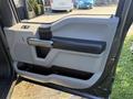 The interior door panel of a 2018 Ford F-150 featuring a window switch and armrest in a light gray and black color scheme