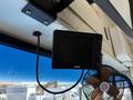 A digital display monitor mounted on the interior of a vehicle with a black cable connected to it