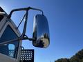 A shiny chrome side mirror of a 2020 Peterbilt 330 truck reflecting its surroundings