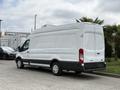 A white 2017 Ford Transit van with a high roof and rear doors positioned slightly ajar, showcasing a sleek and streamlined design