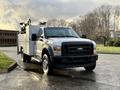 A 2010 Ford F-550 truck with a utility body and orange warning lights mounted on the roof