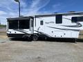 A 2021 Grand Design Recreational ST3478MBS featuring a sleek white exterior with black and gray accents and multiple slide-outs for additional living space