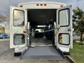 2002 Ford Econoline showing the open rear doors and a wheelchair ramp with interior seating visible