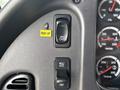 Close-up of the dashboard controls of a 2013 Freightliner 114SD featuring various buttons including speed control and cruise control settings