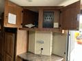 The interior storage area of a 2013 Outdoor Wind River featuring wooden cabinets with doors open and a control panel mounted on the wall