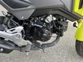 Close-up of the engine of a 2018 Honda Grom showcasing the black Honda branding and mechanical components including the exhaust and frame elements