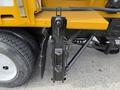A close-up view of a 2016 International 7600's hydraulic lift mechanism attached to the side of the vehicle with visible metal components and bolts