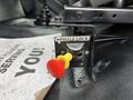 A pintle lock mechanism featuring a yellow push button and a red pull handle mounted on a black metal base