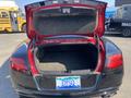 A 2015 Bentley Continental GT with an open trunk revealing a spacious interior and a blue license plate that reads DYSQ