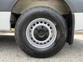 Close-up of a wheel from a 2022 Mercedes-Benz Sprinter showing a silver hubcap and a black tire with tread patterns