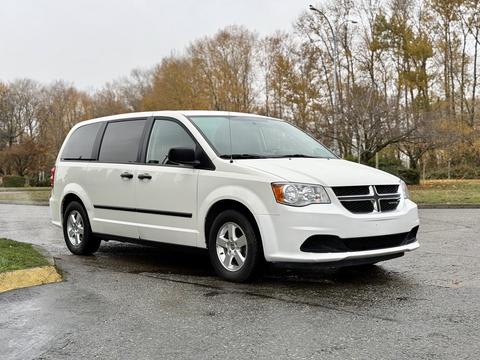 A white 2011 Dodge Grand Caravan is parked with its side facing the viewer showcasing its sliding doors and five-spoke wheels