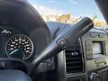 The interior view of a 2018 Ford F-150 showing the gear shift lever with buttons for drive mode and a digital speedometer in the background displaying speed and gear position