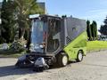 A 2015 Tennant 636 Green Machine street sweeper with a compact body and dual front brushes for cleaning surfaces