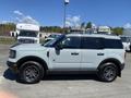 A 2023 Ford Bronco Sport in light green color with black accents and a sleek design parked on a lot with various vehicles in the background
