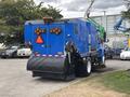 A blue 2013 International DuraStar 4300 street sweeper with a large front brush and warning lights on the rear