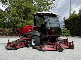 2012 Toro Groundsmaster featuring a cab and multiple cutting decks for mowing grass with large wheels for maneuverability