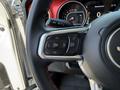 Close-up of the steering wheel of a 2021 Jeep Wrangler featuring control buttons for audio navigation and phone connectivity