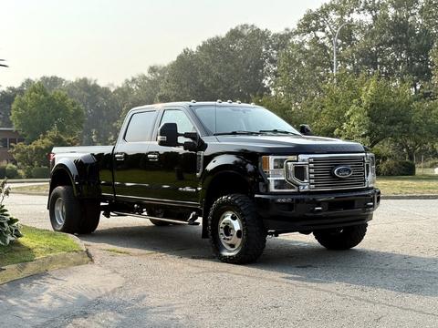 A black 2021 Ford F-350 SD truck with a large grille and high clearance is parked, showcasing its powerful design and robust tires