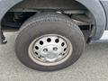 Close-up of a tire mounted on a 2023 Ford Transit with a silver wheel rim featuring circular cutouts and visible tread patterns on the tire