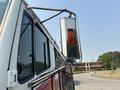 A 1999 Freightliner FL80 featuring a chrome mirror and an amber turn signal light mounted on the side of the vehicle