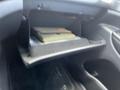 A black glove compartment containing a closed notebook in a 2015 Jeep Grand Cherokee