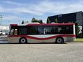 A 2016 Grande West Vicinity bus with a red and cream design parked at an angle showing its side profile and large windows