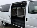 A 2013 Ford E-350 with an open sliding door revealing two gray interior seats inside the van