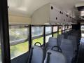 Interior of a 2009 International 3000 CE school bus featuring a row of gray seats and large windows with a view outside