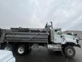 A white 2003 International 5600i dump truck with a raised bed and large tires is parked and facing to the right