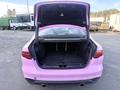 A pink 2020 Jaguar XE with its trunk open revealing a spacious cargo area and a black interior lining