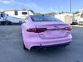 A pink 2020 Jaguar XE parked with a clean design featuring a sleek rear end and dual exhaust pipes
