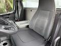The interior of a 2005 Freightliner M2 106 featuring a driver's seat and an empty passenger seat with a console in between