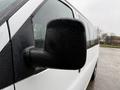 A close-up of the side mirror of a 2021 Chevrolet Express with raindrops on its surface