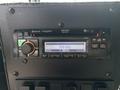 A Jensen car stereo with Bluetooth capability and an LCD screen displaying 590 KHz on a control panel with various buttons and dials