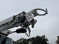 A 2013 Freightliner 114SD truck equipped with a crane arm featuring a large hook attachment for lifting heavy objects
