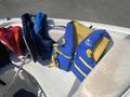 A selection of life jackets in red blue and yellow colors arranged on a boat seat