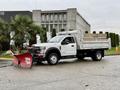 A 2021 Ford F600 truck with a dump bed and a snow plow attachment in the foreground