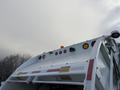 A white 2010 Autocar Xpeditor garbage truck with multiple lights on the roof and warning signals visible