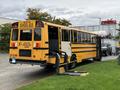 A yellow 2014 Freightliner B2 school bus with large windows and a ramp for accessibility parked on a grassy area