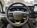A close-up view of the steering wheel and dashboard of a 2023 Ford Transit featuring controls and a digital display screen