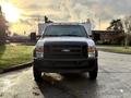 A 2010 Ford F-550 truck facing forward with a white body and black grille equipped with orange rooftop lights