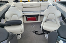 Interior view of a 2013 Larson 238 featuring two white captain's chairs and a central storage area with a red access panel