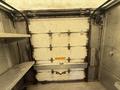 A 2012 Ford Econoline with a large rear cargo door and shelving on both sides of the interior space